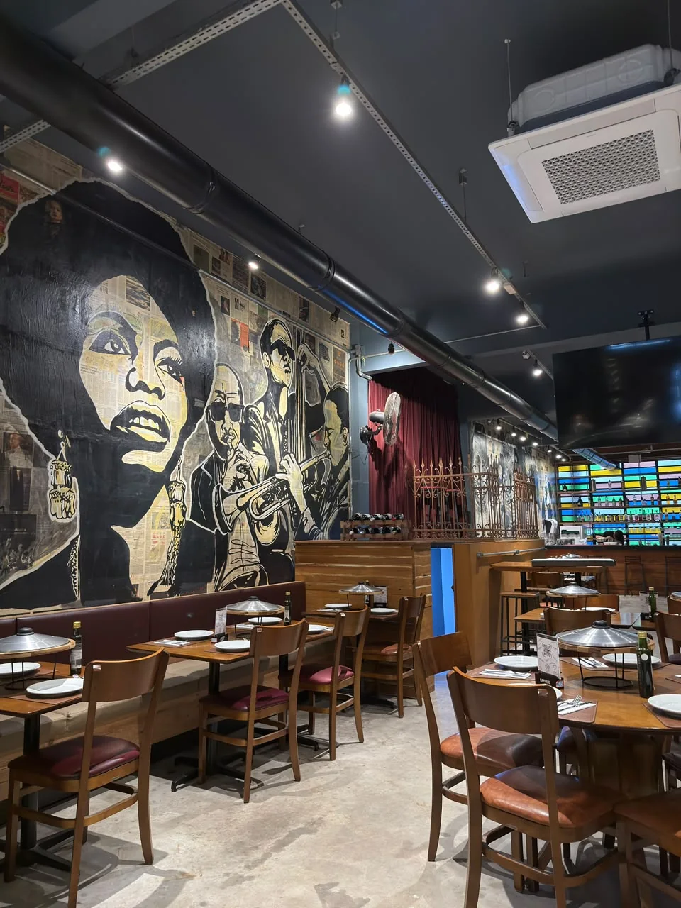 Salão da Vila109 com mesas postas e mural na parede
